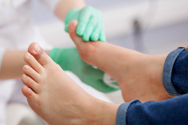 A person s feet being attended to by a medical professional, with one foot receiving treatment and the other being cleaned or inspected.