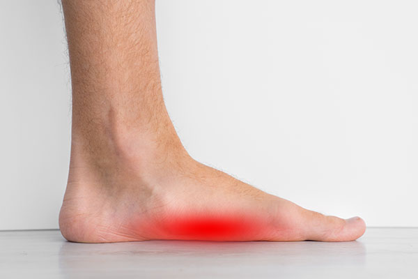 An adult human foot with a red spot on the sole, against a white background.